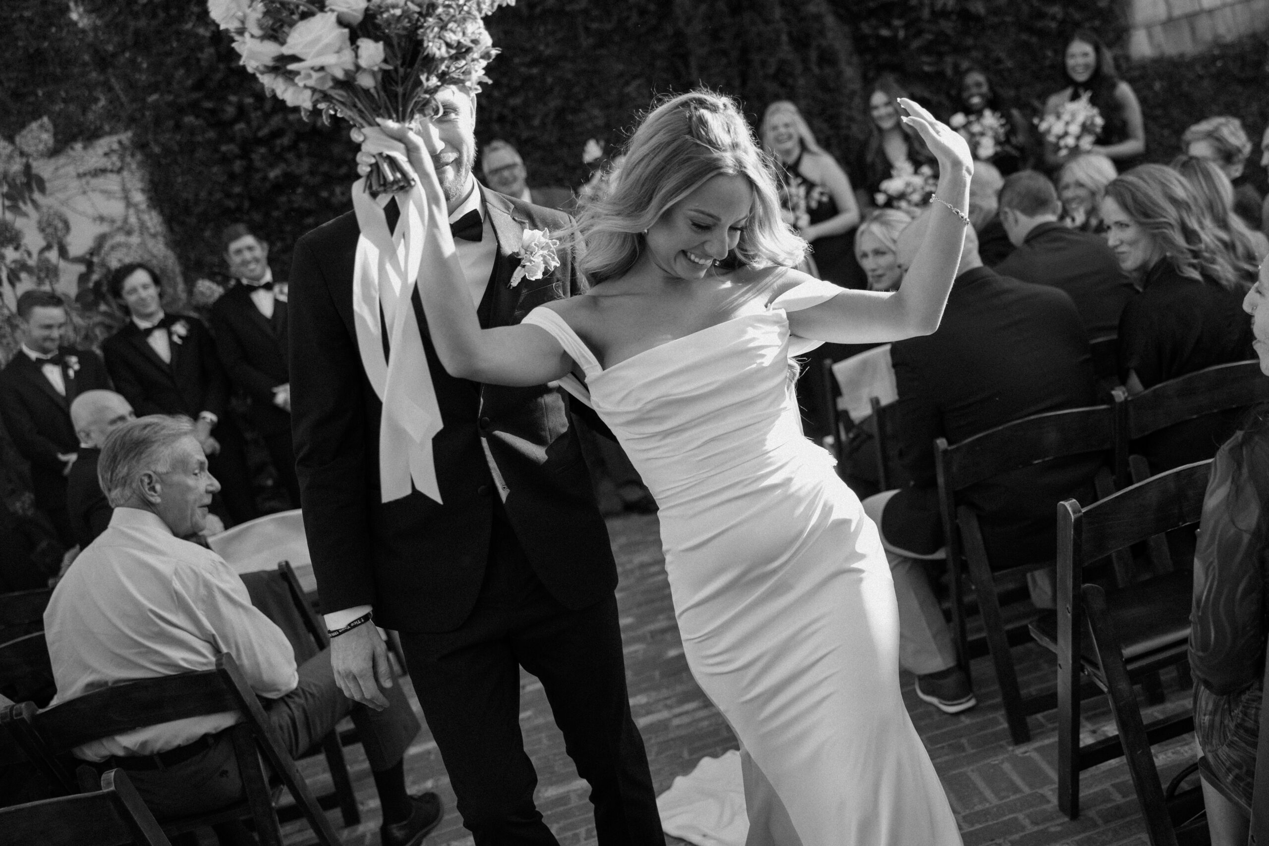 Bride and groom celebrating joyfully as they walk down the aisle, surrounded by smiling guests during their Charleston wedding ceremony