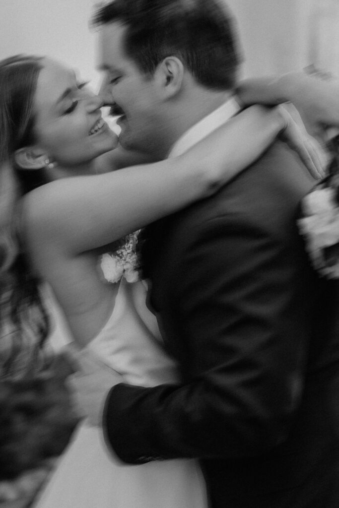 Blurry photo of the bride and groom romantically laughing while embracing each other face to face in the rain