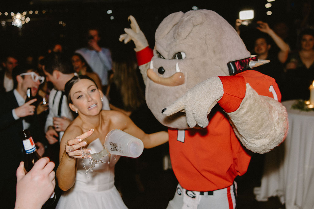Bride has cocktail drink in hand knocked off by the UGA mascot Harry dawg during the fun and rowdy wedding reception