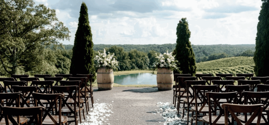 Outdoor wedding ceremony at Montaluce Winery in Dahlonega, Georgia overlooking rolling vineyards, a reflective pond, and surrounding mountain landscape